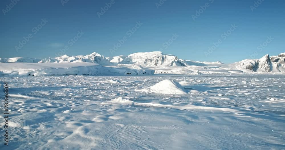 Antarctica snow-covered mountain winter landscape with towering mount range in background. Drone flight over frozen polar ocean coast. Antarctic travel exploration. Discover the beauty of South Pole Antarctica snow-covered mountain winter landscape with towering mount range in background. Drone flight over frozen polar ocean coast. Antarctic travel exploration. Discover the beauty of South Pole