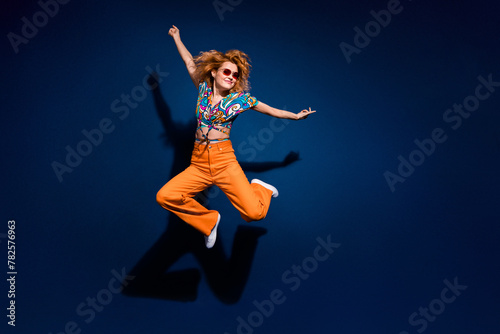 Full size photo of pretty young woman jump empty space ad wear top isolated on dark blue color background
