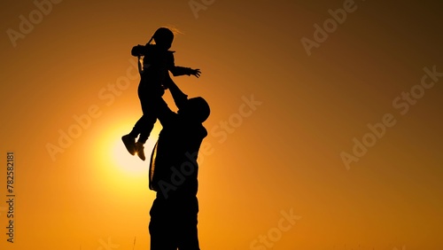 Father throws happy baby daughter into sky. Family game with child in outdoor. Dad is playing with child in park, girl dreams of fly. Happy family concept, childhood dream to fly. Dad kid daughter sun