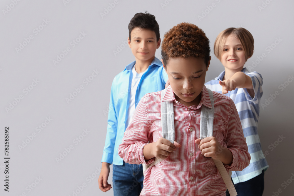 Bullied little African-American boy and his classmates on light background - obrazy, fototapety, plakaty 