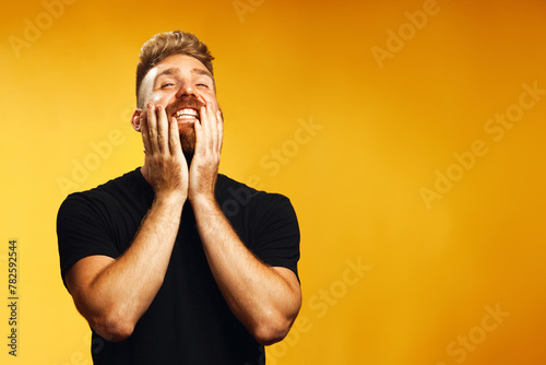 Mister Sunshine concept. Portrait of happy, screaming for joy 35-year-old man with fit body posing over yellow background in black t-shirt. Red hair, modern haircut. Copy-space. Studio shot