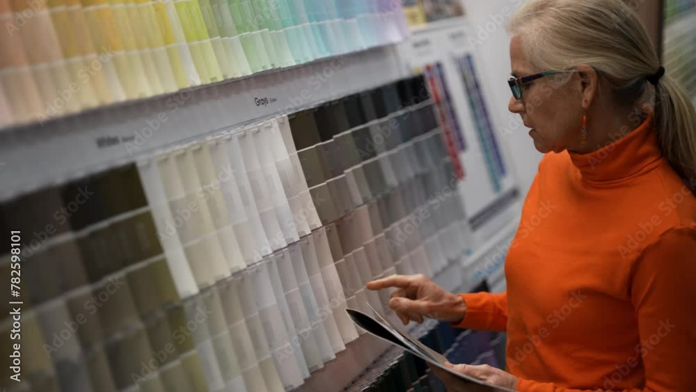 Closeup of mature woman looking at paint chips in a hardware store. Concept of shopping experience for home improvement. Closeup of mature woman looking at paint chips in a hardware store. Concept of shopping experience for home improvement.