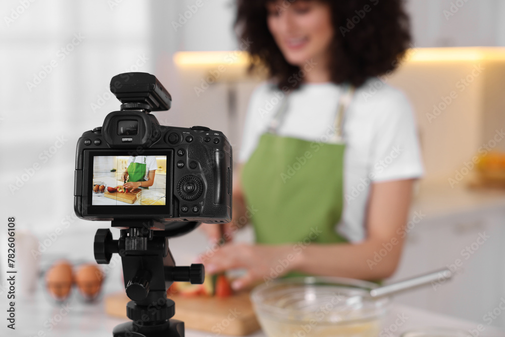 Naklejka premium Food blogger cooking while recording video in kitchen, focus on camera