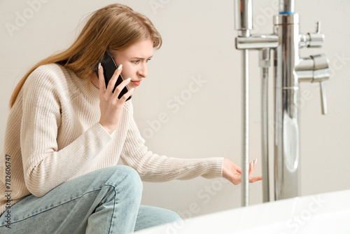 Young woman with mold on wall talking by mobile phone in bathroom