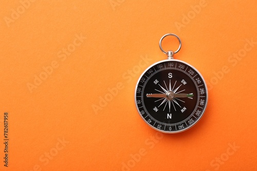 One compass on orange background, top view. Space for text photo