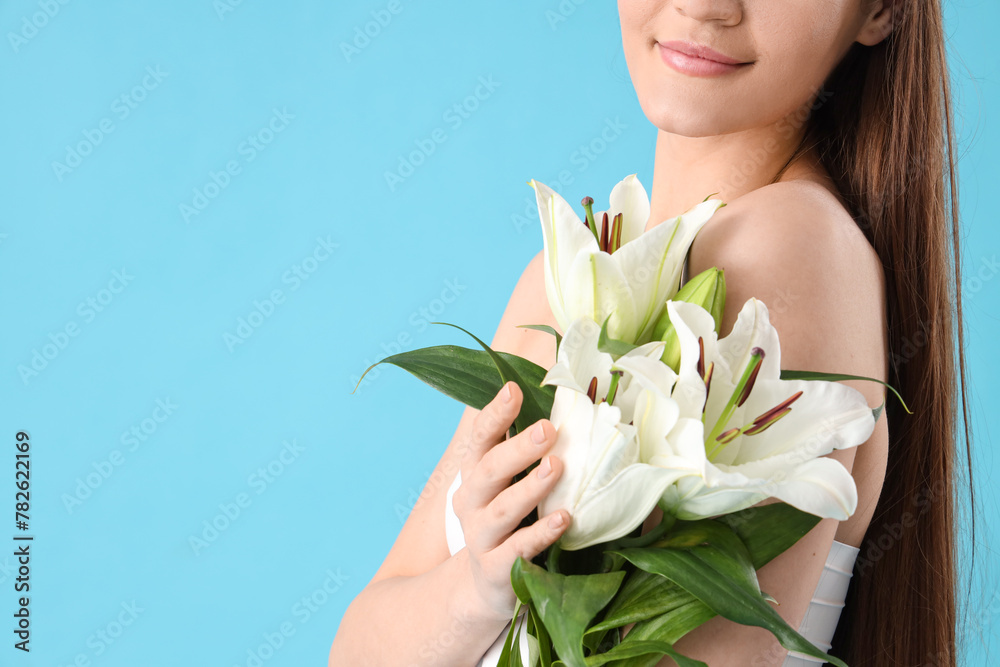 Beautiful young happy woman with white lily flowers on blue background, closeup