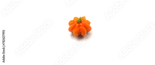 an isolated pitanga. small orange fruit. small green and orange fruit.