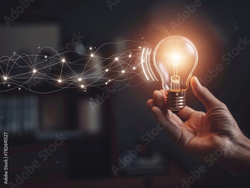 A hand holding a glowing bulb, with digital waves broadcasting outwards, symbolizing bright ideas photo