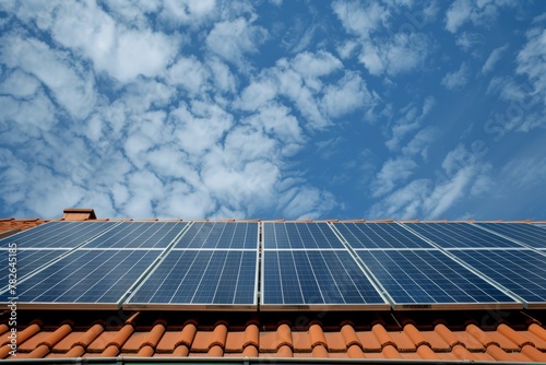 Roof-mounted solar panels with blue sky and clouds in the background