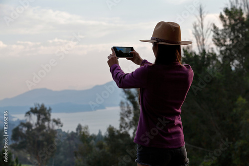 Woman photographing sunset with a celular phone © Fernando