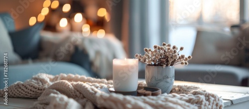 Candles and a cozy blanket placed on a coffee table in a stylish living room setting, creating a warm and inviting atmosphere