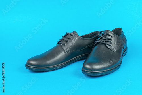 Stylish black leather shoes on a blue background.