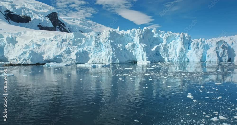 Natural beauty of towering glacier in glacial lake. Blue sky in sunny day. Nature winter landscape. Melting glacier background. Ecology, melting ice, climate change, global warming. Aerial drone shot Natural beauty of towering glacier in glacial lake. Blue sky in sunny day. Nature winter landscape. Melting glacier background. Ecology, melting ice, climate change, global warming. Aerial drone shot