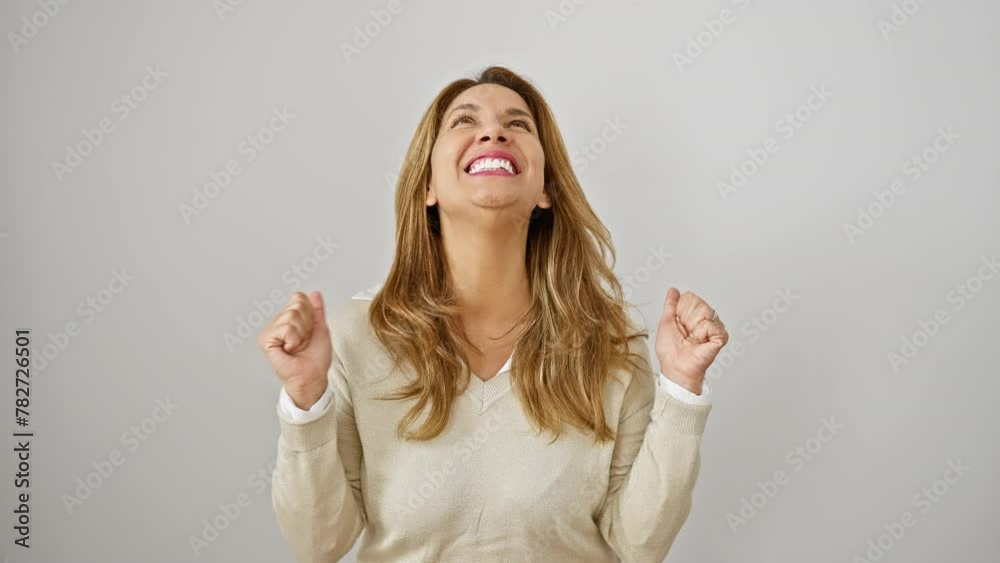 Joyful young latin woman celebrating winning moment, expressing victory with a confident smile, standing isolated on a white background