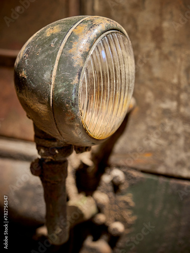 A closeup picture of a greenish, rusty head light on an very old and dirty tractor with nice bokeh.