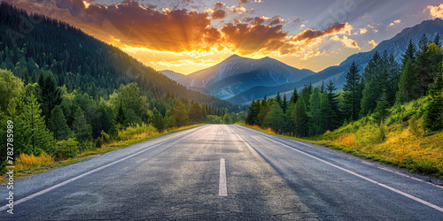 Straight asphalt road in the forest with the view of the mountains with beautiful clouds at sunrise