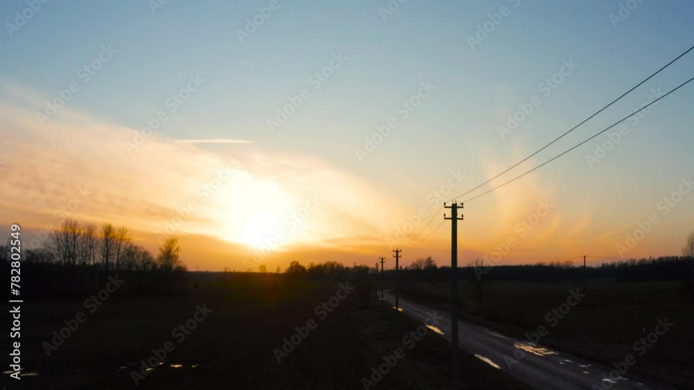 Moody aerial view during golden hour with electric power line near gravel road Moody aerial view during golden hour with electric power line near gravel road