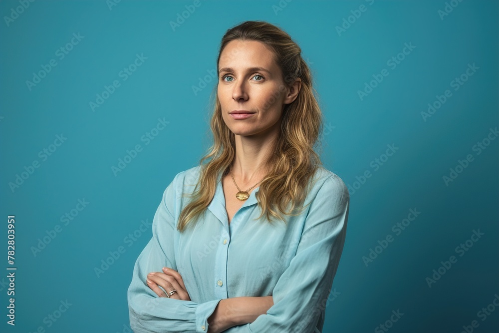 A woman in a blue shirt is standing with her arms crossed A woman in a blue shirt is standing with her arms crossed