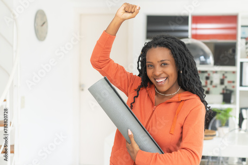Portrait of successful cheering black woman with yoga mat © Daniel Ernst