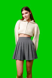A woman wearing a white sweater and a gray skirt stands in a casual pose, showcasing her stylish outfit.