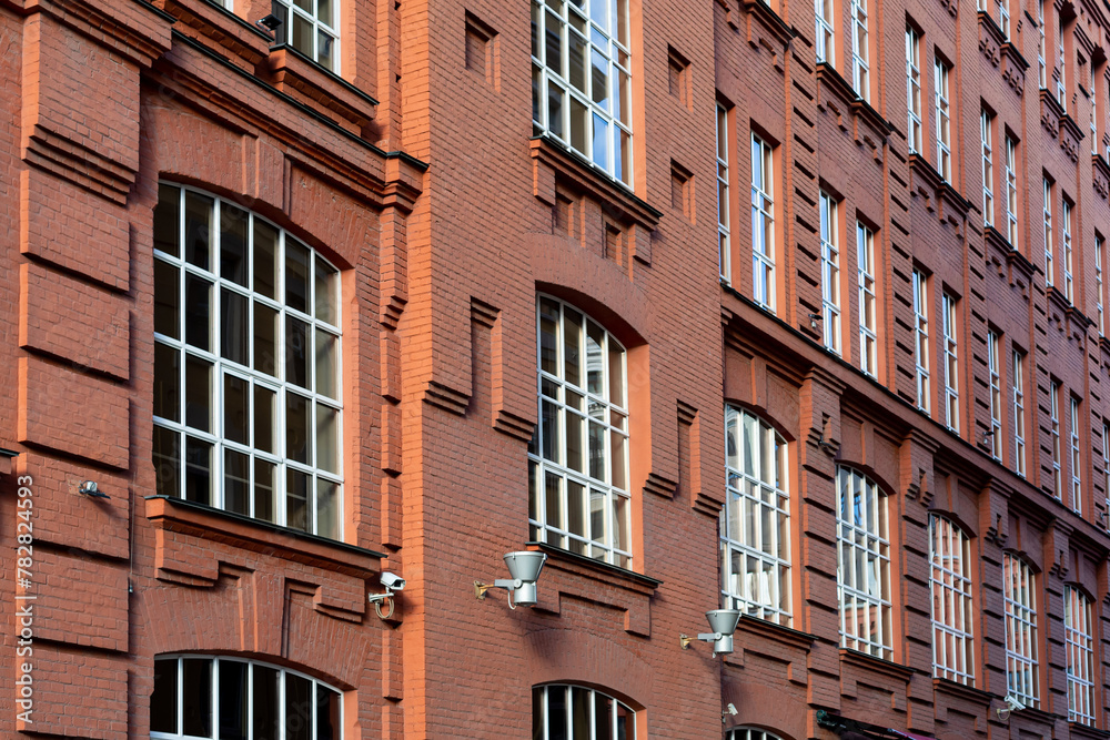 Fototapeta premium Facade of old classic red brick building with large windows with white frames