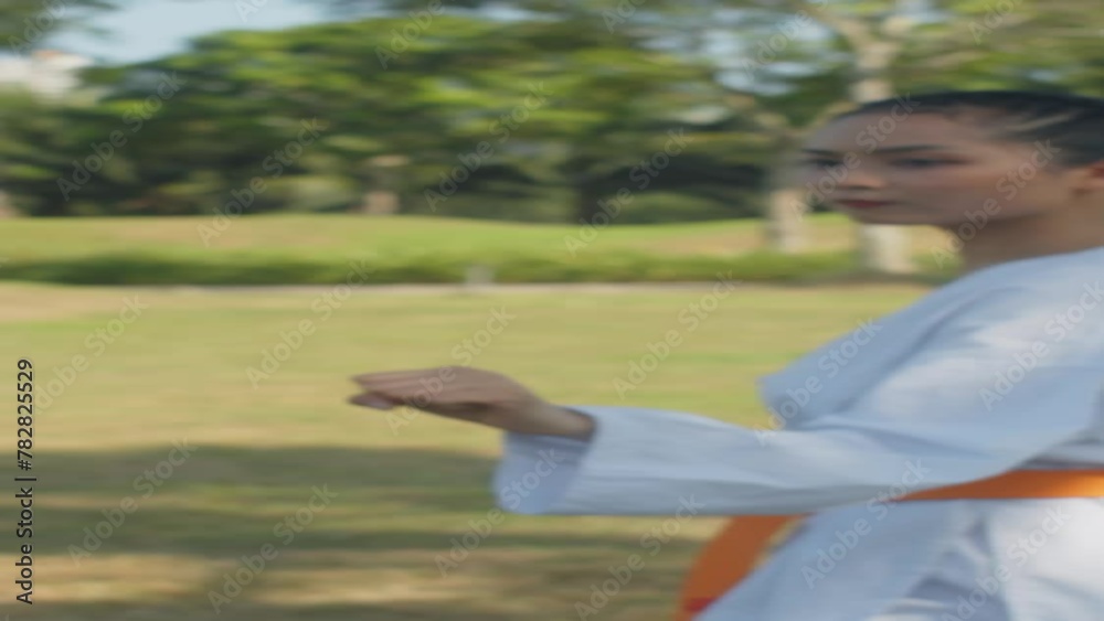 Vertical shot of gen Z Asian sportswoman breaking board while practicing taekwondo with partner outdoors Vertical shot of gen Z Asian sportswoman breaking board while practicing taekwondo with partner outdoors