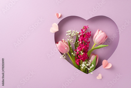 Celebrate Mom: Top view of tulips, hyacinth, gypsophila, and paper hearts framed in heart cutout on pastel violet. Ideal for heartfelt messages or promotional content, leaving space for customization
