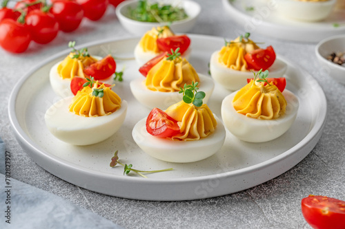 Deviled eggs with cheese, mustard and microgreens on top on a plate for Easter.