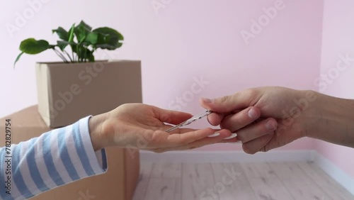 Handing over the keys of a house by a real estate agent to a young woman who rented or bought an apartment. Close-up of the hand of the former homeowner handing the key to the new owner in slow motion