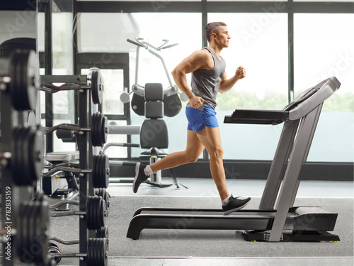 Fit young man running on a treadmill at a the gym © Ljupco Smokovski