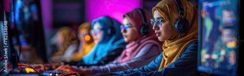 Group of Arab women wearing hijabs and glasses sit in front of a computer screen, engaged in analyzing data for their esports team