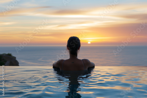 Silhouette of a woman sitting on the water at sunset on a peaceful beach  enjoying the evening waves and the freedom of nature