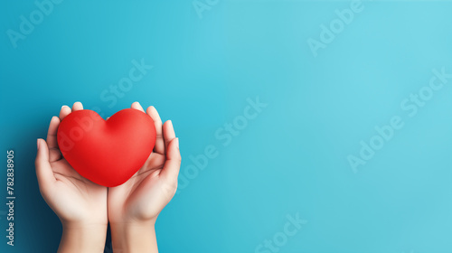 Hand holding red heart on aqua background, Donation, CSR concept, World heart day, world red cross day