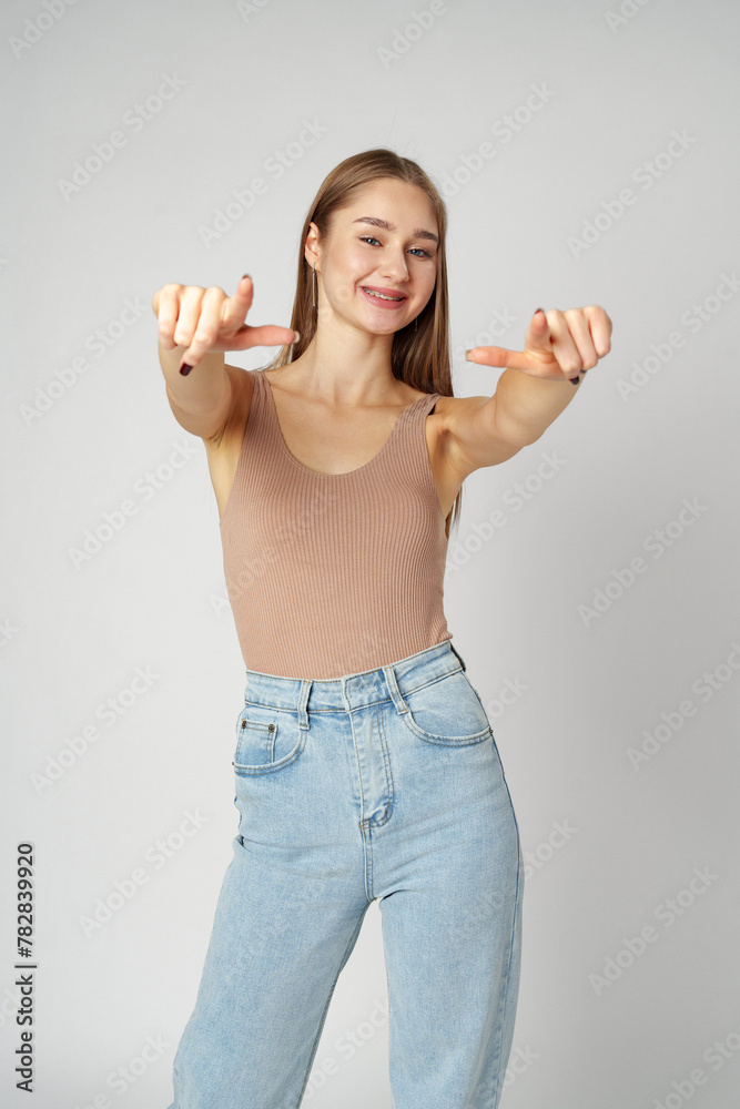 Young Woman Pointing Towards Camera With a Playful Expression in a Studio Young Woman Pointing Towards Camera With a Playful Expression in a Studio