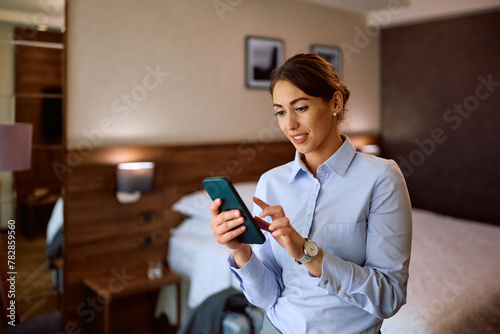 Young female entrepreneur texting on cell phone in  hotel room.
