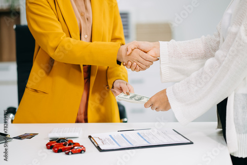 Asian people car salesman or sales manager offers to sell a car and explains of signing a car contract and signing car insurance document .