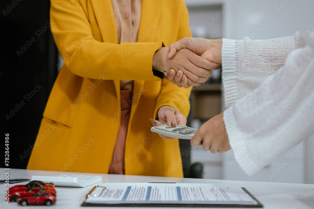 Obraz premium Close up shake hands, Car Dealership and sign contracts in car showrooms or car dealership offices, successful deal.