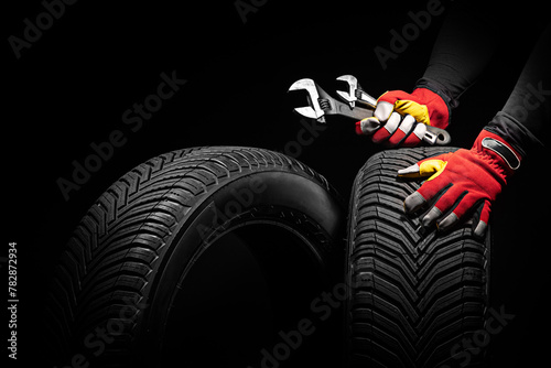 Car tire service and hands of mechanic holding new tyre and wrench on black background with copy space for text