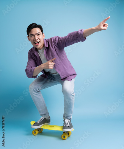 Photo of younf Asian man skating on blue background photo