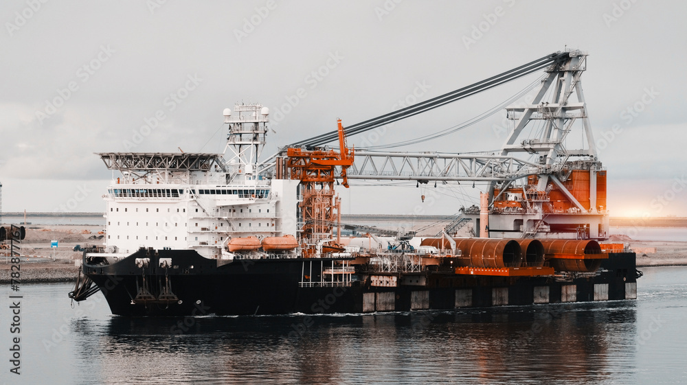 Wind Generators And Offshore Construction Crane Vessel With The Cargo Of Monopiles On Deck. Ship With Motion Compensated Pile Gripper And 8-point Anchor Mooring System.
