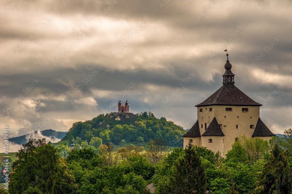 Fortified historical building in mountain landscape with hills after rain with fog. New Castle and Calvary in Banska Stiavnica, Slovakia