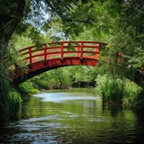 A peaceful image of a red wooden bridge over a lush green riverbank.