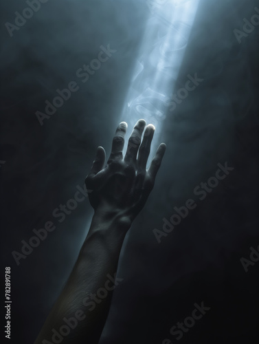 Hand in the dark hand reaches for the ray of light. Hope, loneliness, faith, depression concept