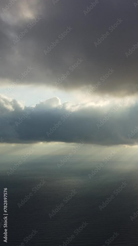 Aerial vertical view. Rays of sun breaking through Dramatic moody and gloomy rain clouds over sea. Abstract aerial nature summer ocean. Vacation, travel and holiday concept. Weather and climate change Aerial vertical view. Rays of sun breaking through Dramatic moody and gloomy rain clouds over sea. Abstract aerial nature summer ocean. Vacation, travel and holiday concept. Weather and climate change