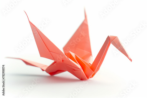 An orange origami crane with sharp folds and shadows, presented in a side profile against a neutral background