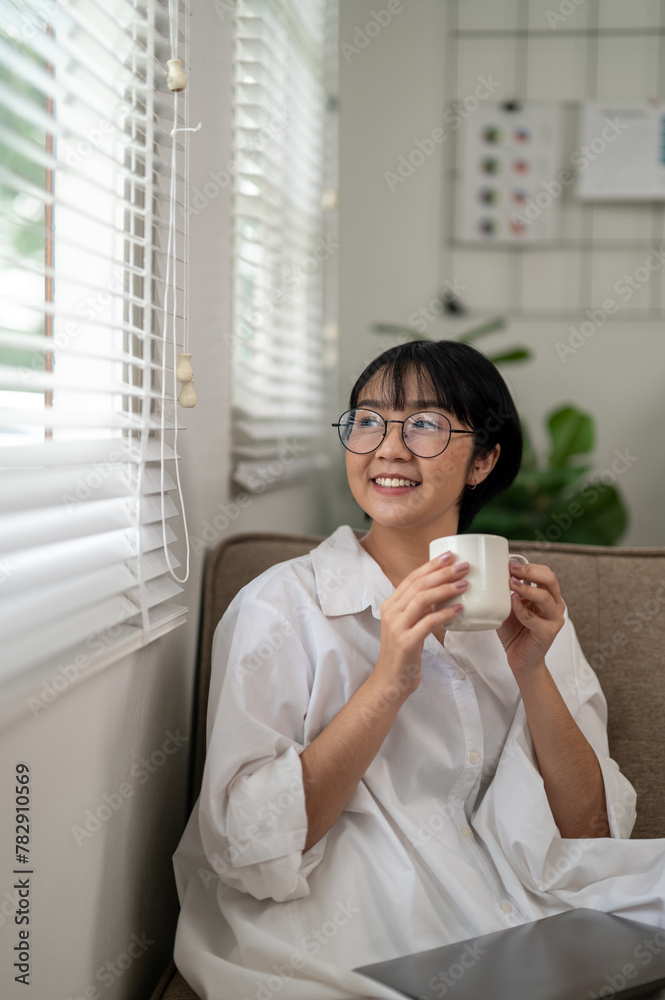 An adult woman sips her coffee while engaging with a laptop in a bright home office, reflecting a moment of tranquility amidst a busy workday. An adult woman sips her coffee while engaging with a laptop in a bright home office, reflecting a moment of tranquility amidst a busy workday.