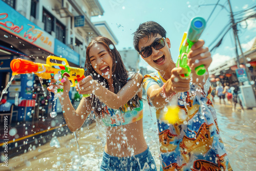 Happy traveler asian man and woman wearing summer shirt holding colorful squirt water gun over blur city, Water festival holiday concept