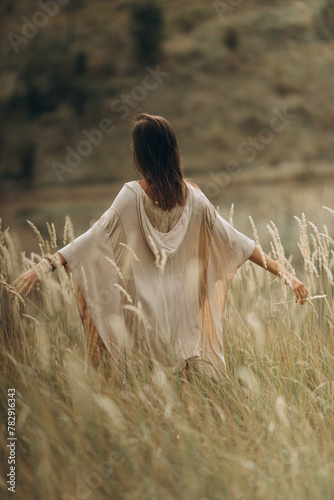 Woman and spirituality, a young female in light clothes meditates and contemplates nature. Side view of Caucasian woman and relaxation