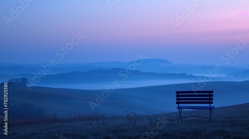 Solitary bench overlooking foggy hills at dawn.
