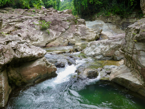 Mountain river with stone banks. A mountain river stream flows over rocks in the jungle. A mountain river forms a cascading waterfall.